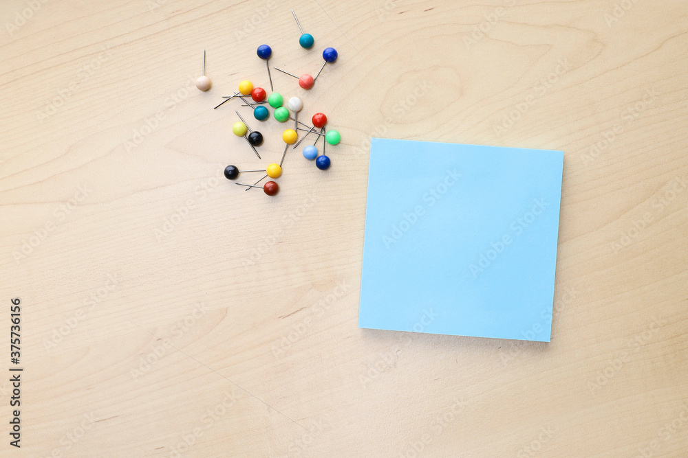 Wall mural view from above of an empty post-it note and group of push pins on the wooden table