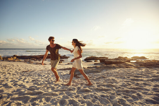 Happy young couple walking on a beach at sunset