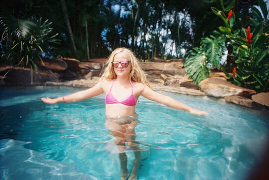 girl in pool in pink bikini in sunglasses