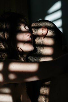 Man biting his spouse's neck in a striped shadow