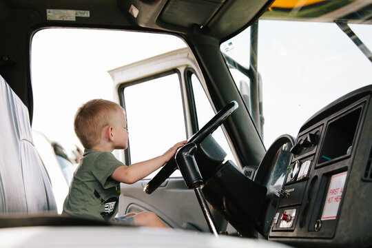 A little boy pretending to drive a large truck.