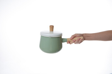 a hand holding a green pot with a lid on it.