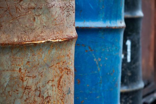 Rusty old metal drum lined up outside the warehouse.