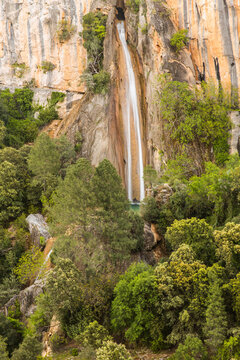 waterfall flowing from a hole in the wall of a mountain
