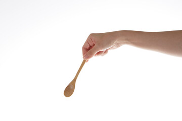 hand holding teaspoon made of wood.