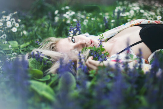 Young beautiful woman with blond hair, freckles and blue eyes lying in the grass