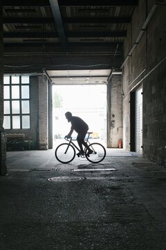 Young Man Balancing on Fixed Gear Bicycle in Abandoned Factory