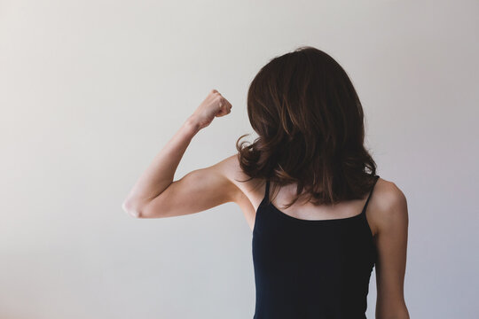 Thin woman flexing her arm muscle - horizontal