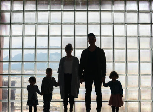 Sillouette of family standing together in front of window grid