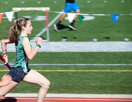 Teenage girl in first place at a track meet in the 4x100 relay