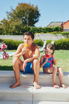 Brother and sister eating icecream in the family yard after a swim