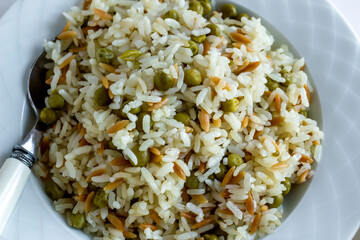 Traditional Turkish rice pilaf with peas and noodles in plate,top view