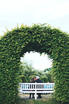 Elderly couple kissing under trellis