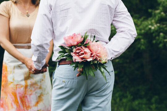 man about to give a bouquet of peonies to a woman