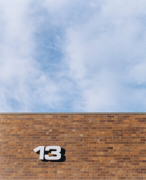 Number 13 on brick wall, sky and clouds above