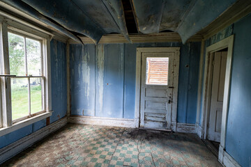 Interior of a blue room, abandoned and decaying, with a rotting floor and collapsing ceiling in Bannack Ghost Town in Montana