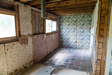 Interior of an abandoned room inside a home in Bannack Ghost town. Peeling wallpaper and cracking floorboards, with exposed beams in ceiling