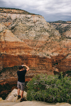young male photographer taking pictures of landscape in zion national park