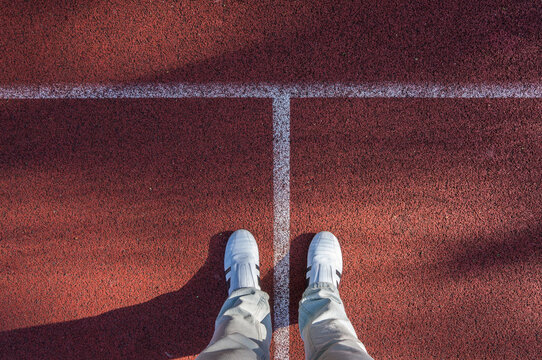 White sneakers on red sport field, footsie, personal perspective