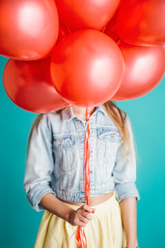 Anonymous woman with red balloons in hand