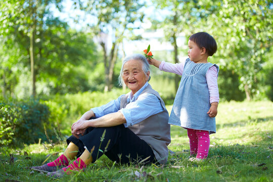 litle asian girl trying to put a flower on her great grandmother's head
