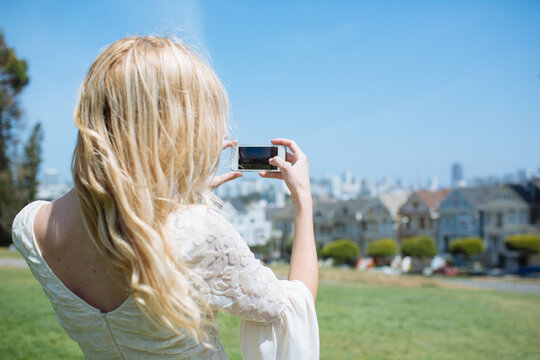 Woman taking the picture to the city of San Francisco with her mobile phone