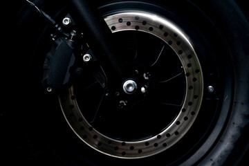 Abstract dark tone beside veiw of Disc Brake of motorcycle with a sparkling light.