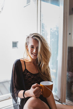 Beautiful Blond Woman Smiling While Having Her Morning Coffee