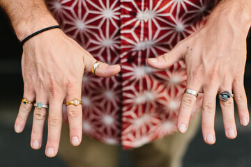 A man showing off his jewelry / rings that he made
