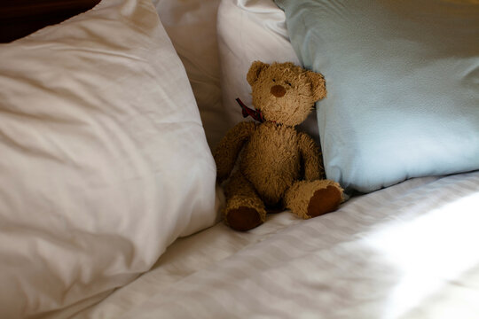 Well loved child's teddy bear on a fluffy white bed