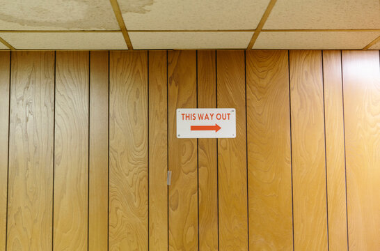 This Way Out Exit Sign on Wood Paneling