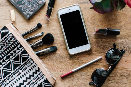A cell phone with makeup and beauty essentials