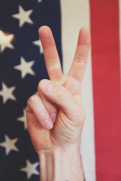 Peace and love finger hand gesture in front of an old American Flag
