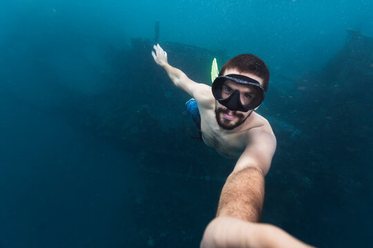 Man taking selfie underwater above a shipwreck