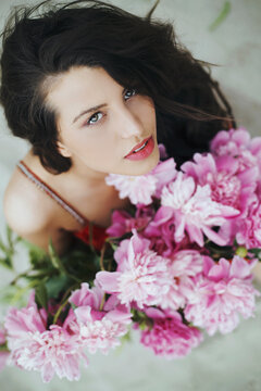Portrait of a beautiful young woman with peonies flowers