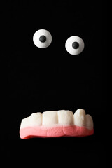 Funny halloween monster, sugar eyes and gummy teeth on a black background