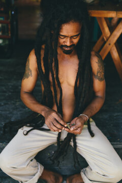 Rasta man with dreadlocks mixing weed in his hands