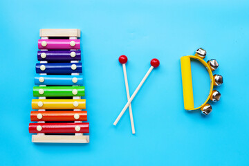 Colorful xylophone with hand bells musical instrument for ringing on blue background.