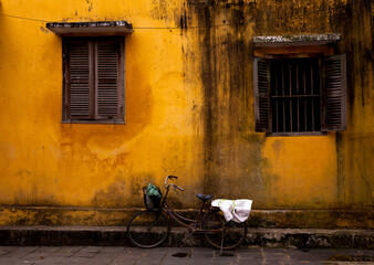 Fototapeta na wymiar Old, weathered bike against colorful, textured wall in Hoi An, Vietnam 