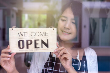 Happy asian women owner turning open sign after lockdown quarantine in modern coffee shop