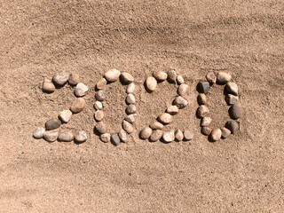 The numbers 2020 are written and lined with stones in the sand. Place for your text. Your text here.