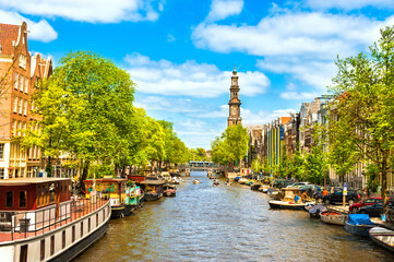 Crowded Amsterdam canal houseboats Westerkerk Church cathedral under brilliant sunny summer sky - obrazy, fototapety, plakaty