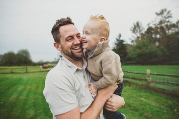 Playful father enjoying young son in farm field