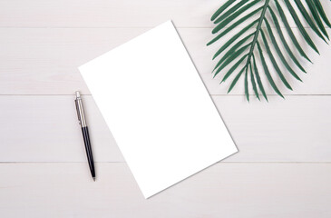 Blank paper sheet copy space with mockup and leaf on wooden table, poster and invitation, postcard...
