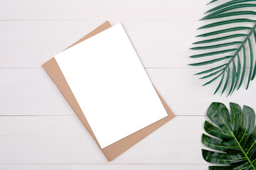 Blank paper sheet copy space with mockup and leaf on wooden table, poster and notebook, postcard decoration your design or branding, simplicity and minimal, nobody, flat lay, top view.