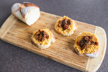 plant-based food, vegan snack with paprika hummus on sliced baguette bread topped with sundried tomatoes