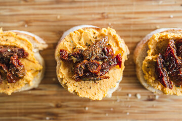plant-based food, vegan snack with paprika hummus on sliced baguette bread topped with sundried tomatoes
