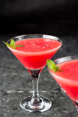 Cocktail in Martini glasses and watermelon. Triangular glasses with a pink drink inside and slices of watermelon