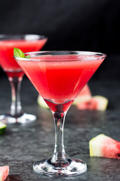 Cocktail in Martini glasses and watermelon. Triangular glasses with a pink drink inside and slices of watermelon
