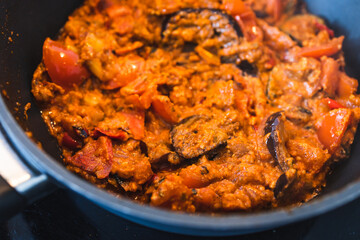 plant-based food, vegan eggplant zucchini and red pepper mix getting sauteed on a pan with mixed spices and red pesto sauce